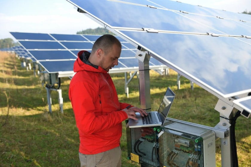male engineer using laptop at solar field panel