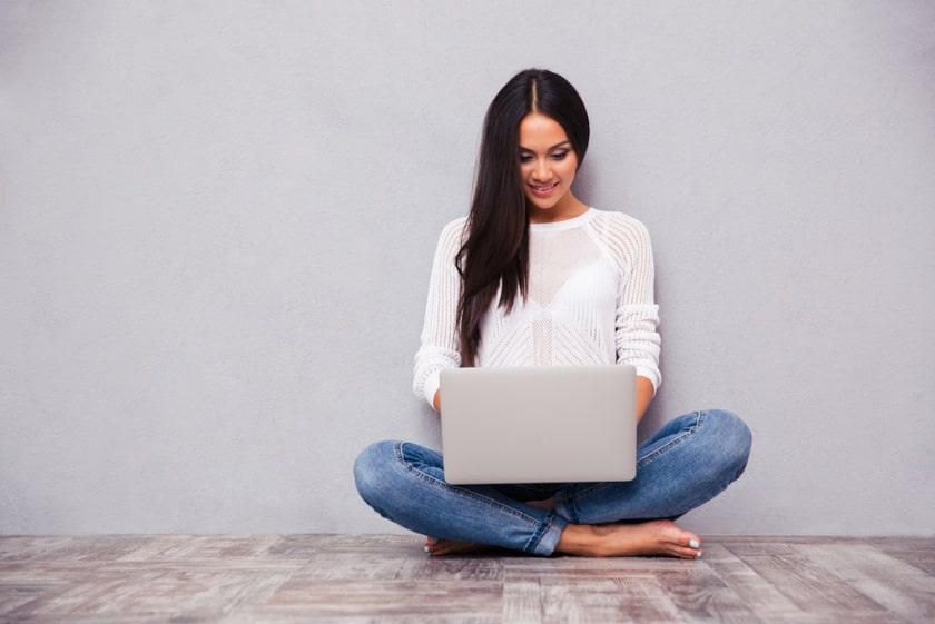 Portrait of a casual woman sitting on the floor with laptop