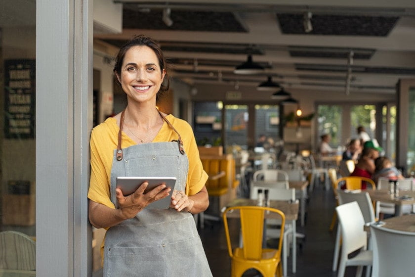 restaurant employee in cafe with digital restaurant inspection checklist app on tablet