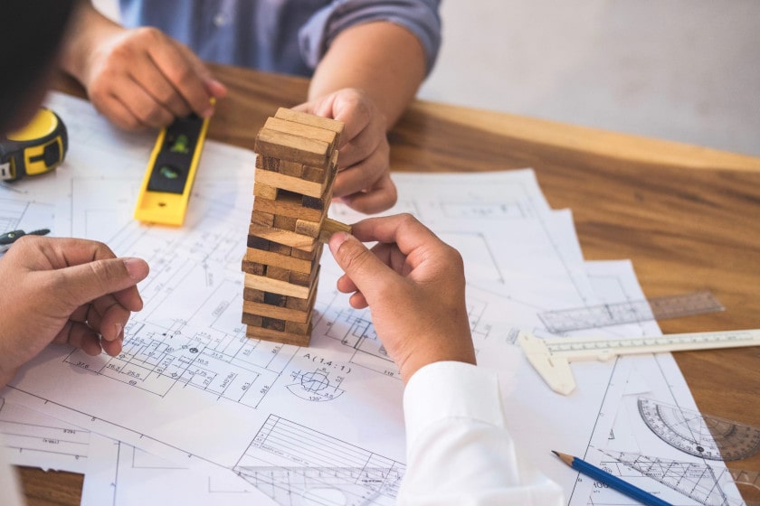 engineering and construction workers building blocks on building blueprints