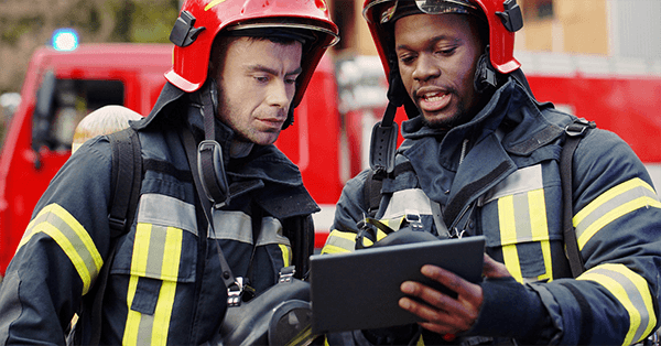 Two men in fire safety gear collecting fire protection deficiencies.