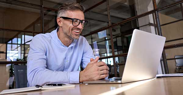 Man in office smiling at computer.